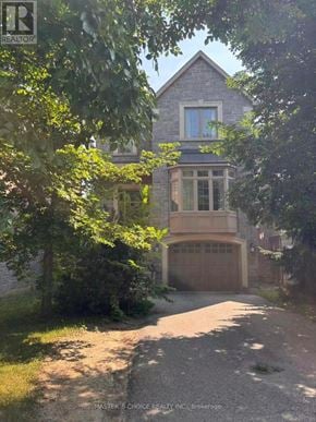 Toronto (Willowdale East) apartment for rent - A house with a garage is surrounded by trees.
