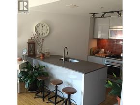 Vancouver apartment for rent - A kitchen with a bar stool and a clock on the wall.