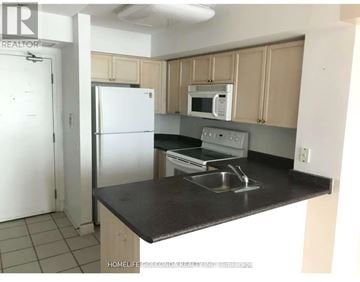 Toronto (Willowdale East) condo for rent - A kitchen with a black countertop and white appliances.