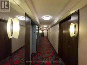 Toronto (Etobicoke West Mall) condo for rent - A hallway with a red carpet and a light on the wall.