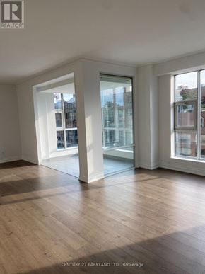 Toronto (Annex) condo for rent - A spacious room with wooden flooring and large windows.