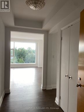 Toronto (Annex) condo for rent - A hallway with a wooden floor and white walls leading to a door.