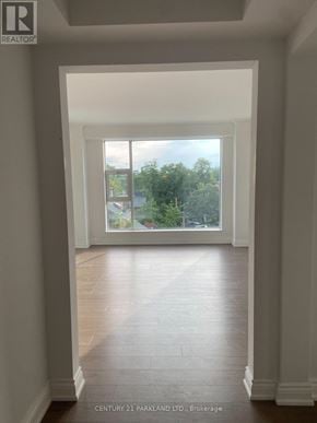 Toronto (Annex) condo for rent - A spacious room with a view of trees through a large window.