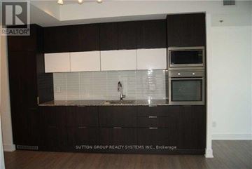 Toronto (Waterfront Communities) condo for rent - A kitchen with dark wood cabinets and a white backsplash.