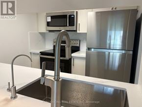 Toronto (Bay Street Corridor) condo for rent - A modern kitchen with a stainless steel sink and refrigerator.