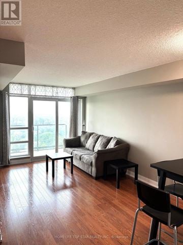 Toronto (Tam O'shanter-Sullivan) condo for rent - A living room with a grey couch and a black chair.