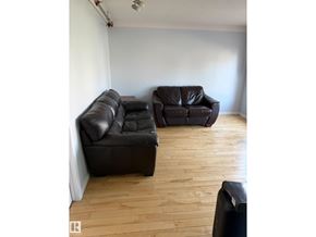 Edmonton apartment for rent - Two black leather sofas in a room with wooden flooring.