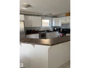 Edmonton apartment for rent - A kitchen with white cabinets and a brown countertop.