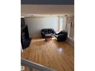 Edmonton apartment for rent - A living room with a black leather couch and a wooden floor.
