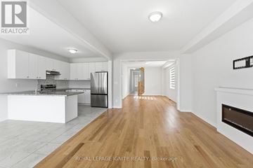 Oshawa (Taunton) apartment for rent - A spacious kitchen with white cabinets and a wooden floor.