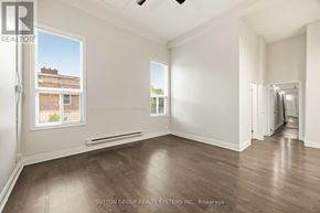 Toronto (Kensington-Chinatown) condo for rent - A room with wooden floors and white walls, with a window showing a view of a building outside.