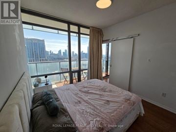 Toronto (Bay Street Corridor) condo for rent - A bedroom with a large bed and a view of the city.