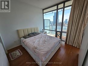 Toronto (Bay Street Corridor) condo for rent - A bedroom with a large bed and a view of the city.
