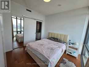 Toronto (Bay Street Corridor) condo for rent - A bedroom with a large bed and a window overlooking a cityscape.