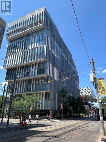 Toronto (Kensington-Chinatown) condo for rent - A modern glass building with a street in front of it.