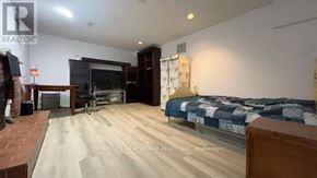 Toronto (Bayview Village) apartment for rent - A bedroom with a bed, a couch, and a television in a room with wooden flooring.
