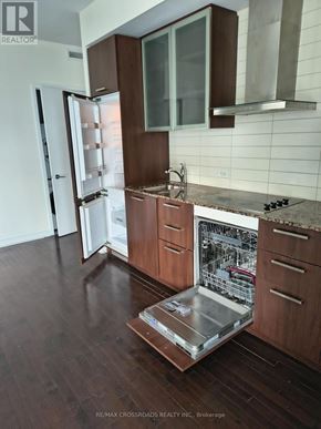 Toronto (Waterfront Communities) condo for rent - A modern kitchen with wooden cabinets and a glass table.
