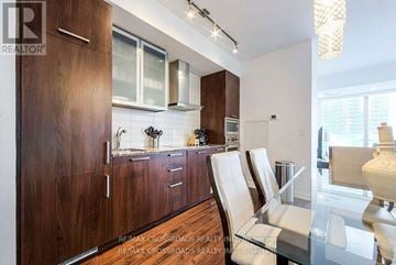 Toronto (Waterfront Communities) condo for rent - A modern kitchen with wooden cabinets and a glass table.