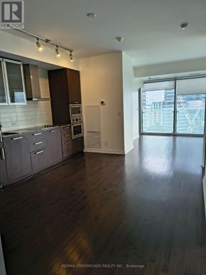 Toronto (Waterfront Communities) condo for rent - A room with wooden flooring and a glass door leading to a balcony.