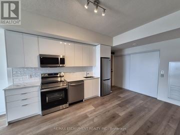 Brantford condo for rent - A kitchen with white cabinets and a wooden floor.
