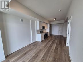 Brantford condo for rent - A spacious room with wooden flooring and white walls.