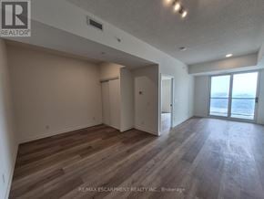 Brantford condo for rent - A spacious room with wooden flooring and a sliding glass door leading to a balcony.