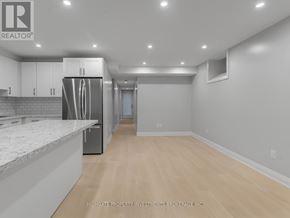 Toronto (Palmerston-Little Italy) apartment for rent - A spacious kitchen with a refrigerator, cabinets, and a marble countertop.