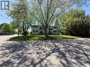 Brantford apartment for rent - A house with a blue frame is surrounded by trees and grass.