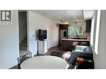 Richmond townhouse for rent - A modern living room with a television and a kitchen area in the background.