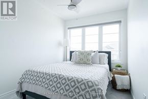 Milton (Cb Cobban) townhouse for rent - A bedroom with a bed, pillows, a ceiling fan, and a window.