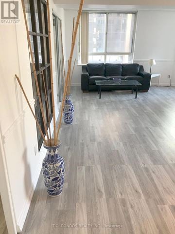 Toronto (Bay Street Corridor) condo for rent - A living room with a black couch and a wooden floor.