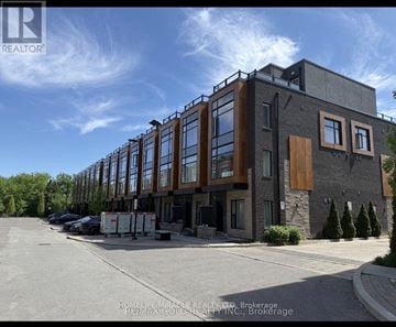 Brampton (Fletcher's Creek South) townhouse for rent - A modern building with a glass facade and a parking lot in front.