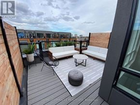 Brampton (Fletcher's Creek South) townhouse for rent - A balcony with a white couch, a black chair, and a round ottoman with a wooden floor and a glass table.
