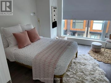 Brampton (Fletcher's Creek South) townhouse for rent - A bedroom with a large bed and a window overlooking a cityscape.