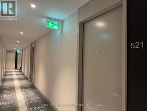 Toronto (Waterfront Communities) condo for rent - A hallway with a green exit sign and a door with the number 521 on it.