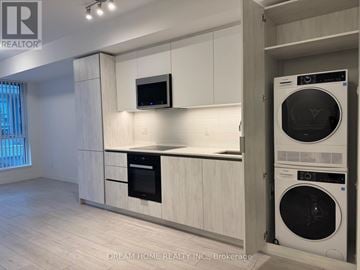 Toronto (Waterfront Communities) condo for rent - A modern kitchen with white cabinets and a black oven.