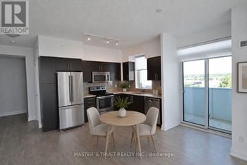 Oakville (Co Central) condo for rent - A kitchen with a table and chairs in the middle of the room.