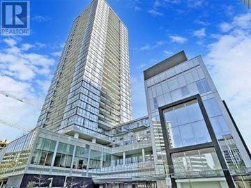 Toronto (Willowdale West) condo for rent - A modern glass building with a clear blue sky in the background.