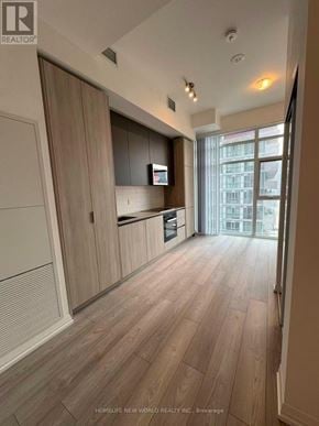 Toronto (Waterfront Communities) condo for rent - A spacious kitchen with wooden flooring and a large window.