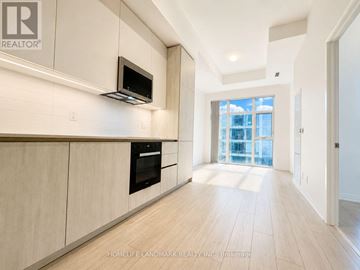 Toronto (Waterfront Communities) condo for rent - A modern kitchen with wooden cabinets and a black microwave above the stove.