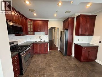 Vancouver apartment for rent - A kitchen with brown cabinets and a black stove top oven.