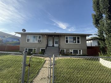 Edmonton apartment for rent - A house with a grey roof and a white fence in front.