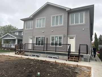 Edmonton apartment for rent - A grey house with a black fence and a man walking in front.