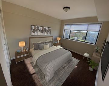 Hyattsville apartment for rent - A bedroom with a large bed and a window overlooking a tree-filled area.