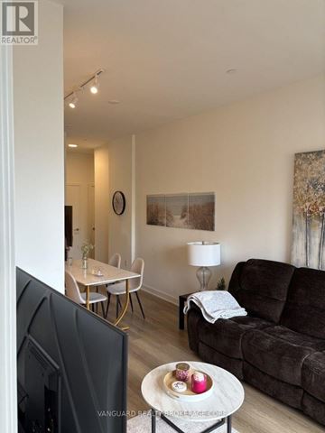 Toronto (Niagara) condo for rent - A living room with a couch, a table, a television and a lamp.
