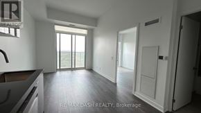 Vaughan (Steeles West Industrial) condo for rent - A spacious, empty room with a large window and sliding glass doors leading to a balcony.