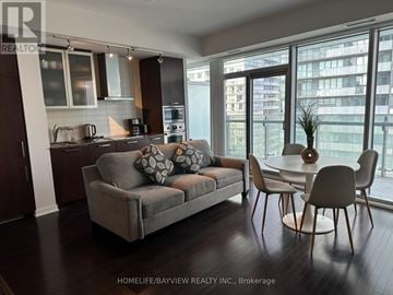 Toronto (Waterfront Communities) condo for rent - A modern living room with a grey couch and a dining table.