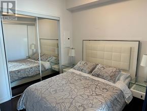 Toronto (Waterfront Communities) condo for rent - A bedroom with a large bed and a glass partition.