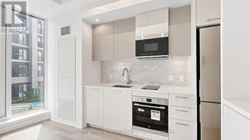Toronto (Regent Park) condo for rent - A modern kitchen with white cabinets and appliances.