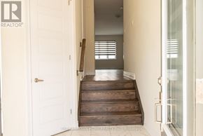 Brantford apartment for rent - A hallway with a white door and a wooden staircase.